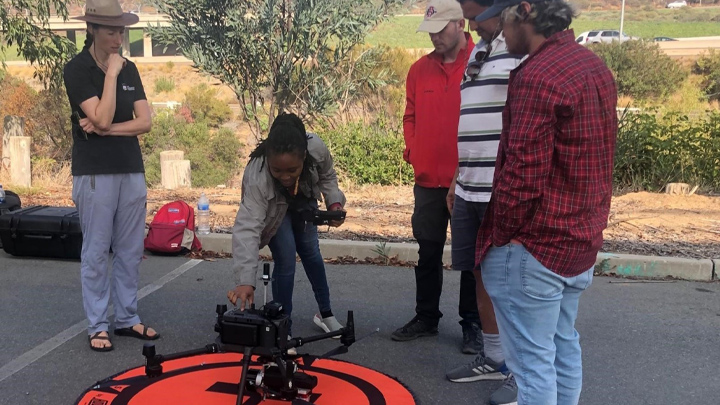 woman fixes drone while group of people watch